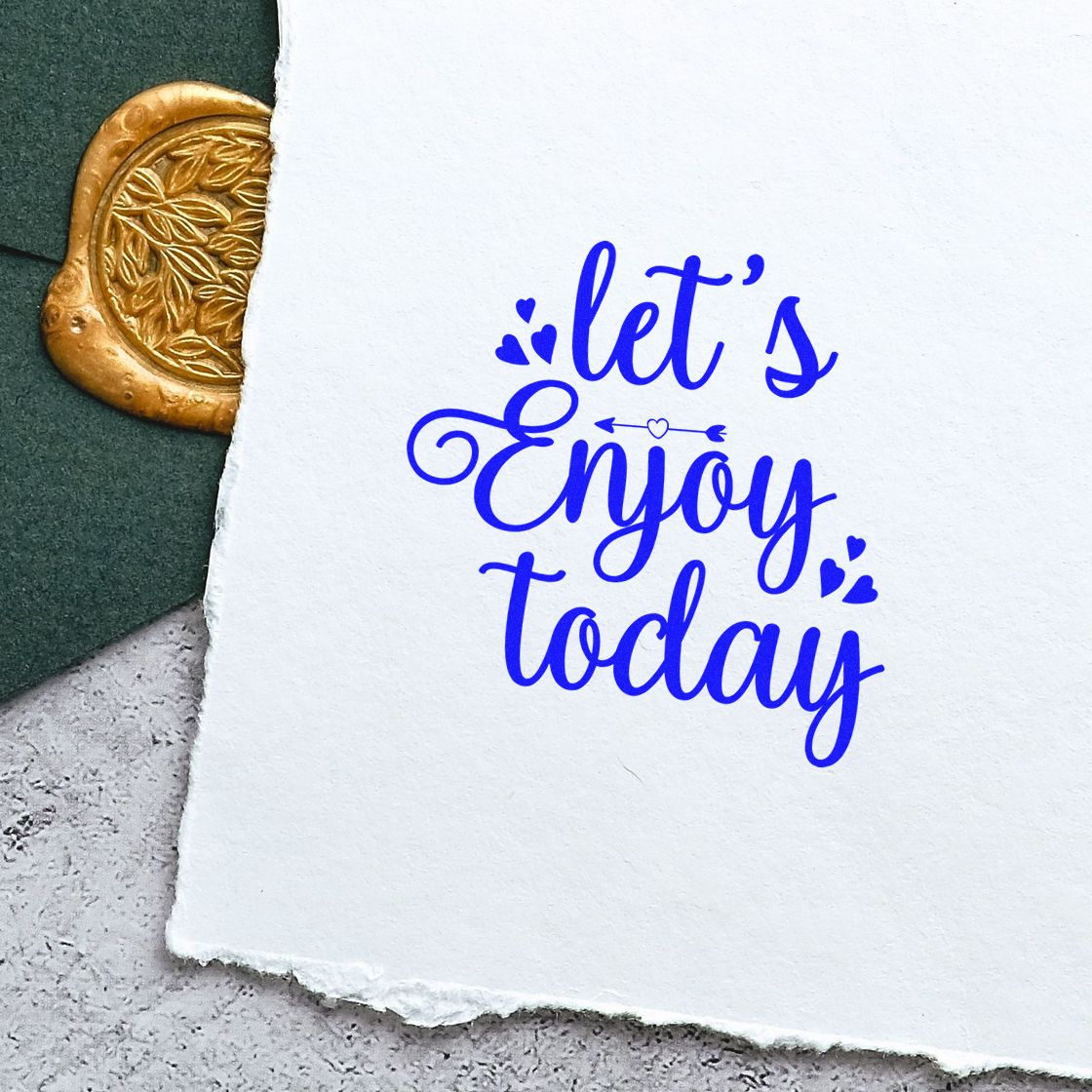 Decorative blue rubber stamp reading lets enjoy today on textured paper, ideal for cards, journaling, and handmade crafts.