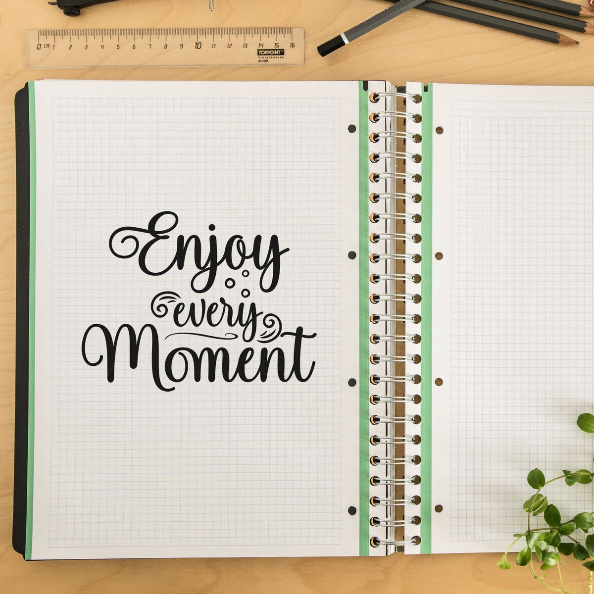 Decorative rubber stamp quote Enjoy every Moment on an open planner notebook for journaling and craft decoration.
