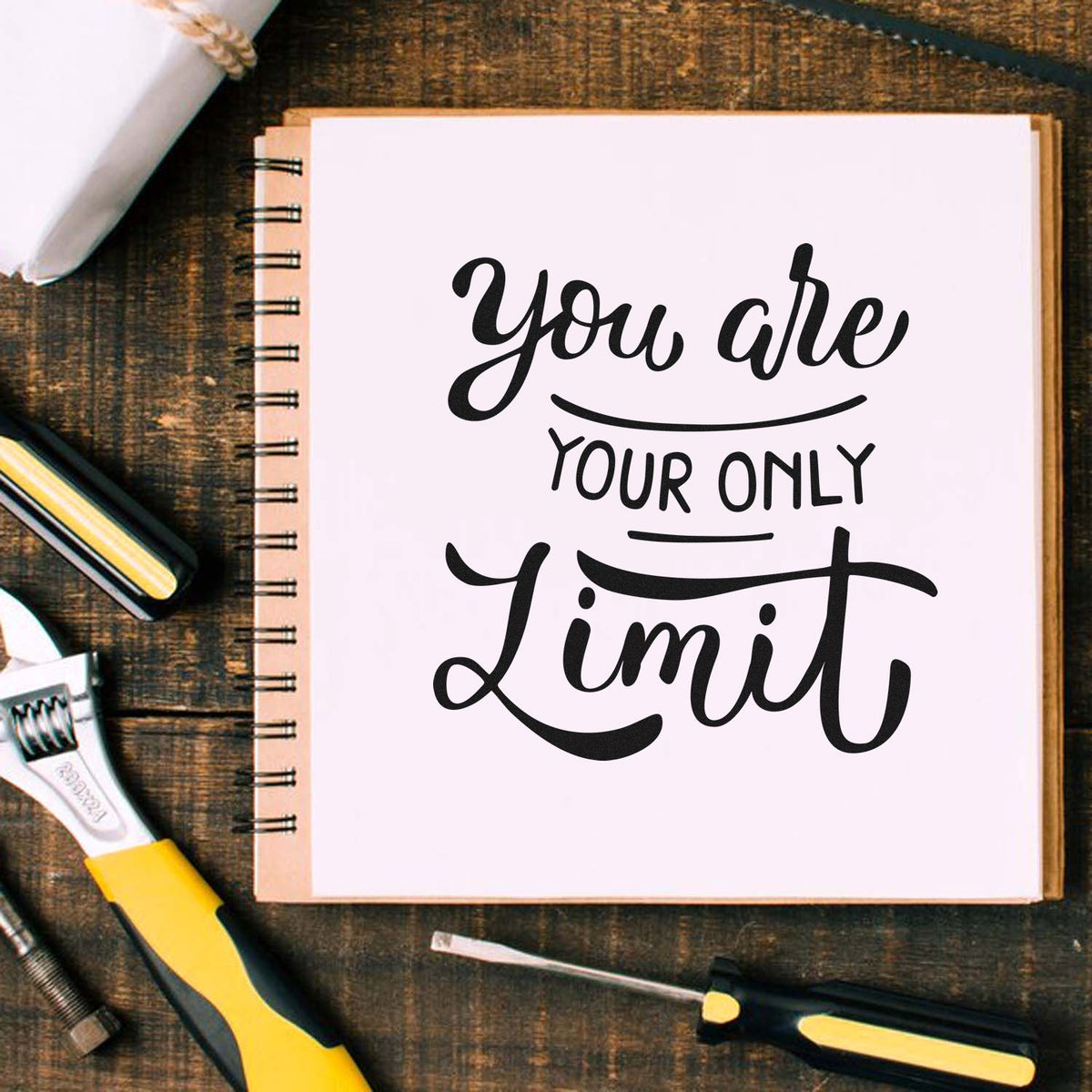 Custom rubber stamp design reading You are your own limit on a notebook, styled with craft tools on a rustic desk.
