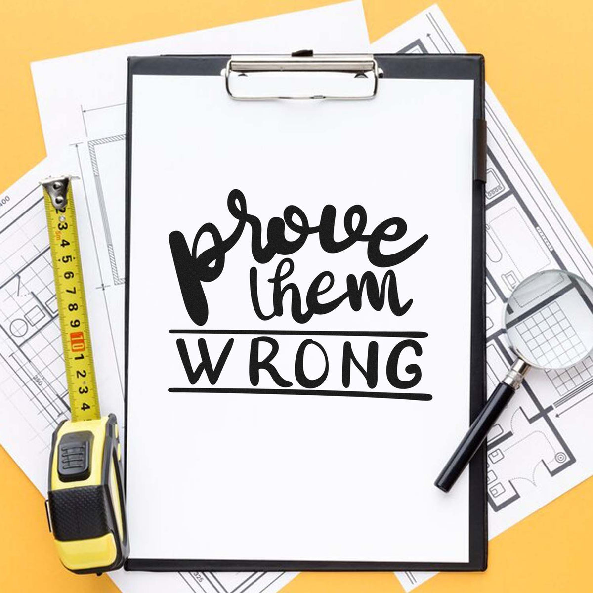 Custom rubber stamp design reading Prove Them Wrong for builders, shown on a clipboard with blueprints and tools.