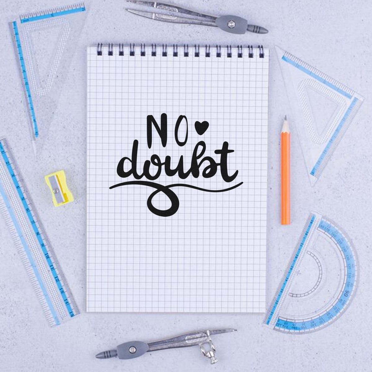 No doubt rubber stamp design on graph notebook with drafting tools and pencil, ideal for stationery and craft projects.