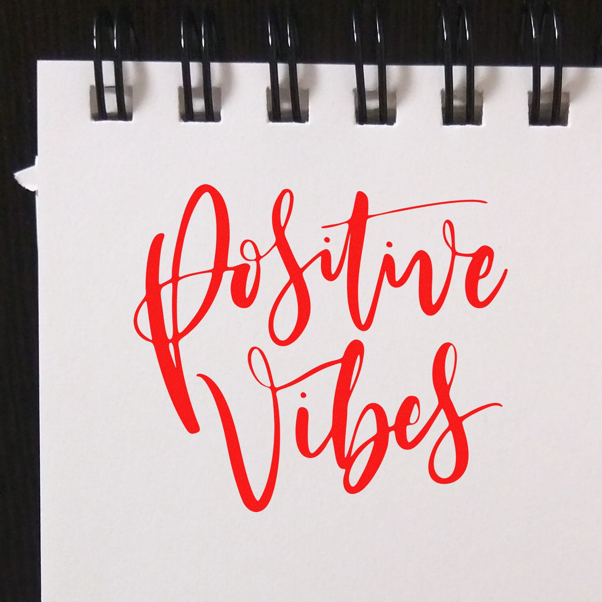 Positive Vibes red script rubber stamp impression on notebook paper, ideal for custom motivational craft stamps.