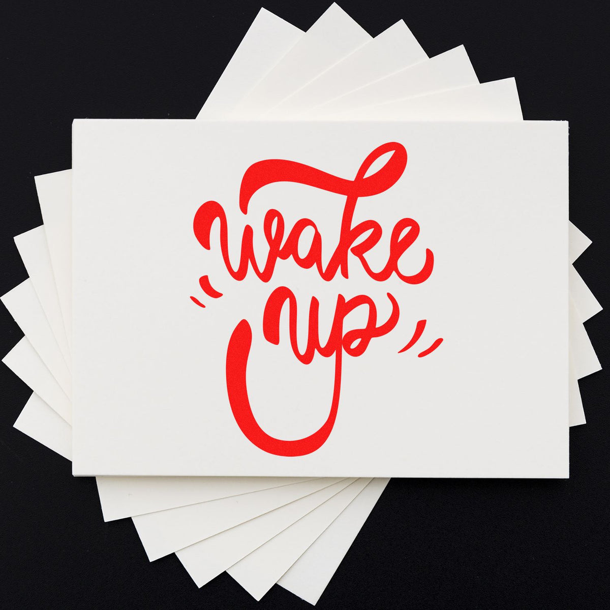 Red Wake Up script rubber stamp design on stacked white cards for stationery and craft use