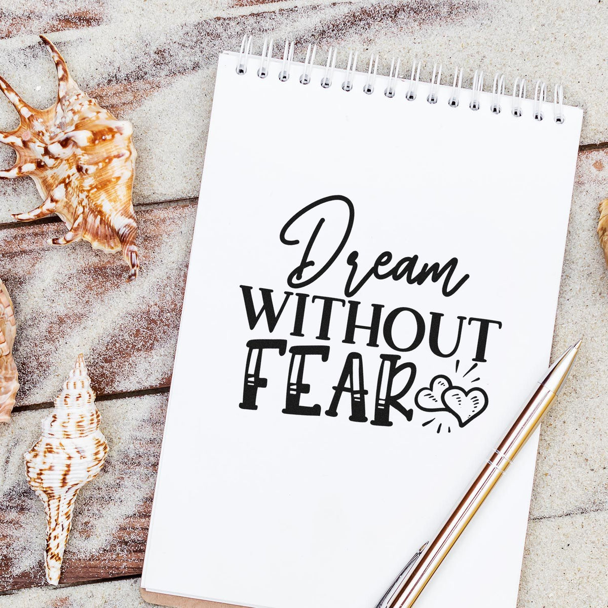 Dream Without Fear rubber stamp design on a notebook, styled with seashells and a pen for coastal-themed journaling.