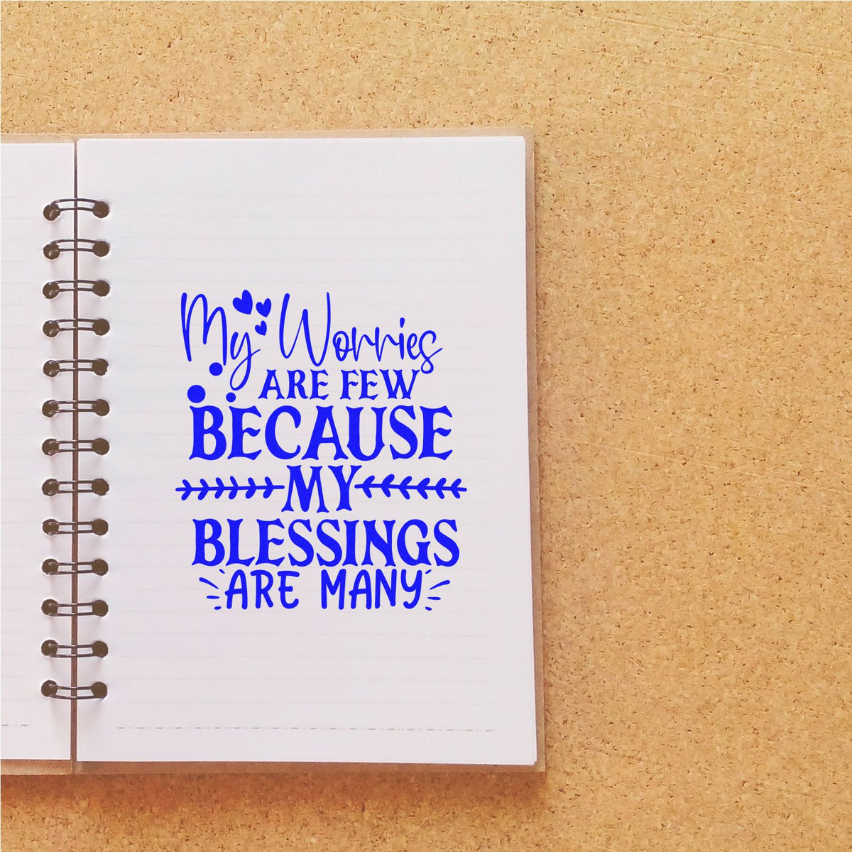 Inspirational rubber stamp design reading My worries are few because my blessings are many on a notebook page.