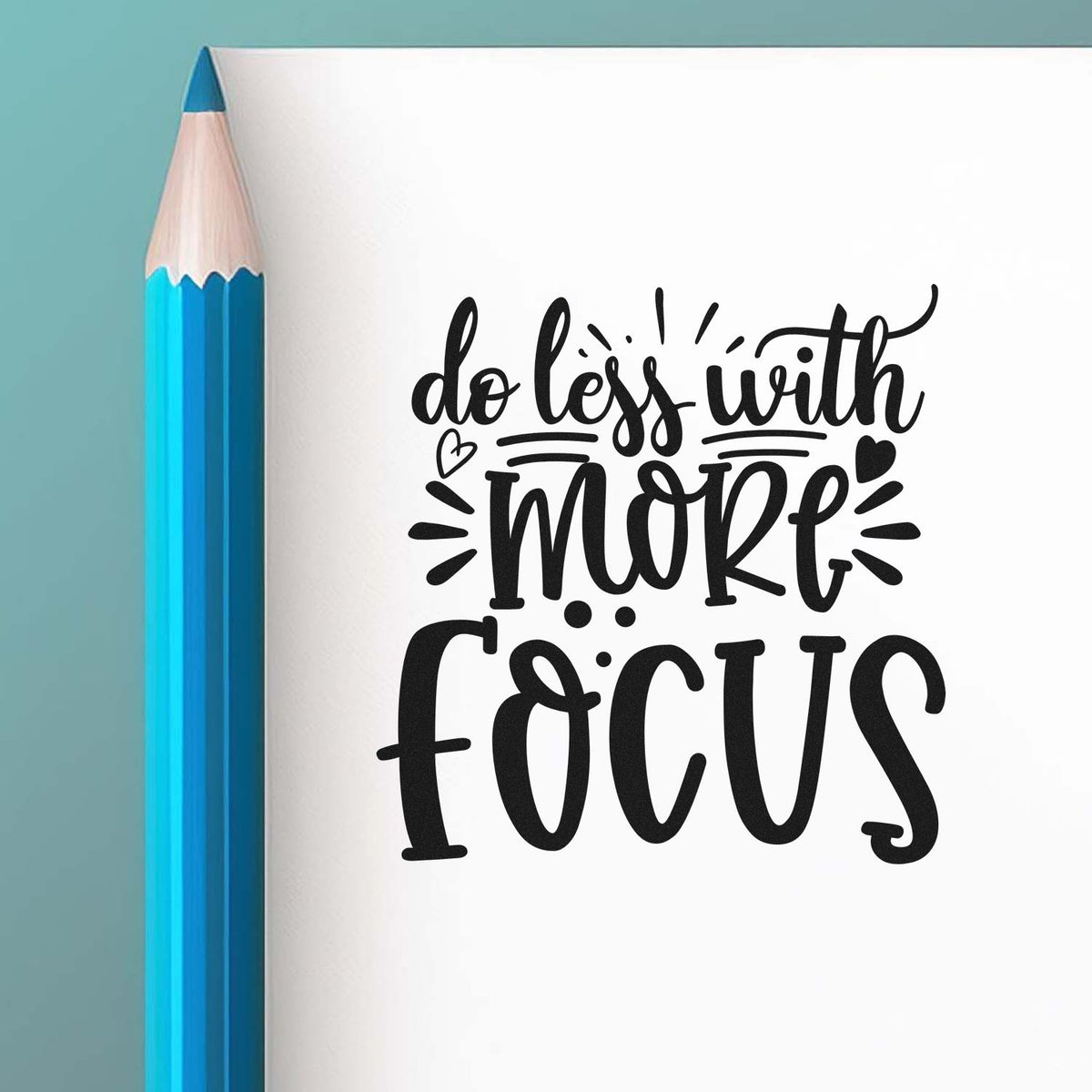 Custom rubber stamp design with motivational quote do less with more focus beside a blue pencil.