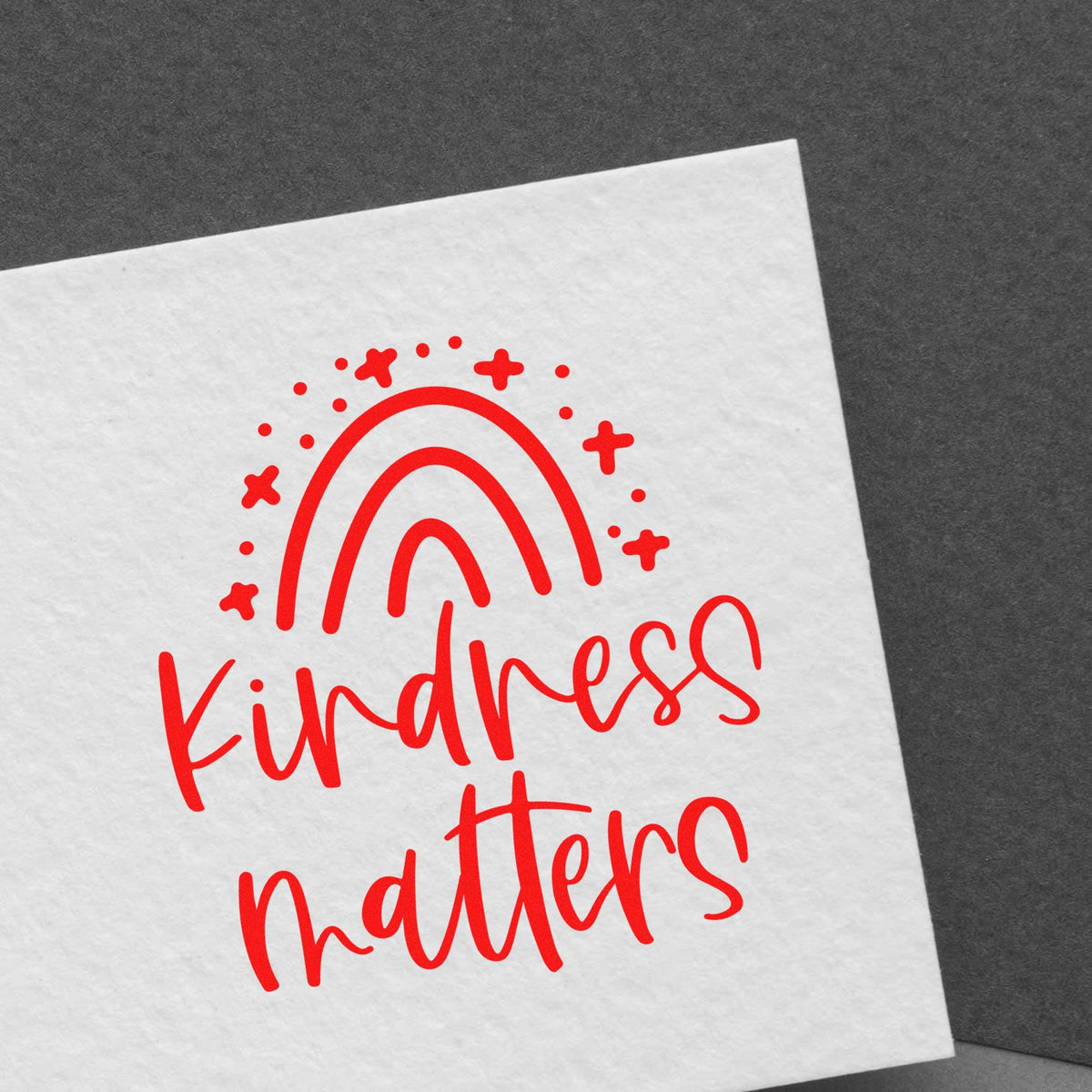 Kindness matters rubber stamp design with red rainbow and script text on white paper