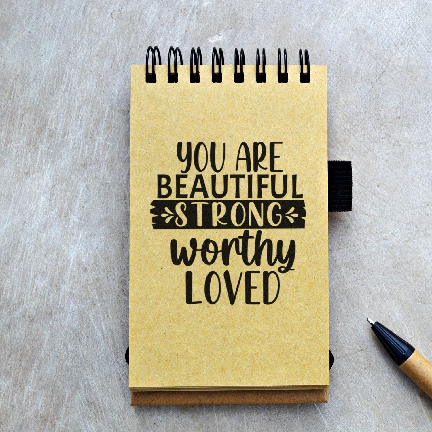 Inspirational rubber stamp on kraft notebook with positive quote: You Are Beautiful, Strong, Worthy, Loved.