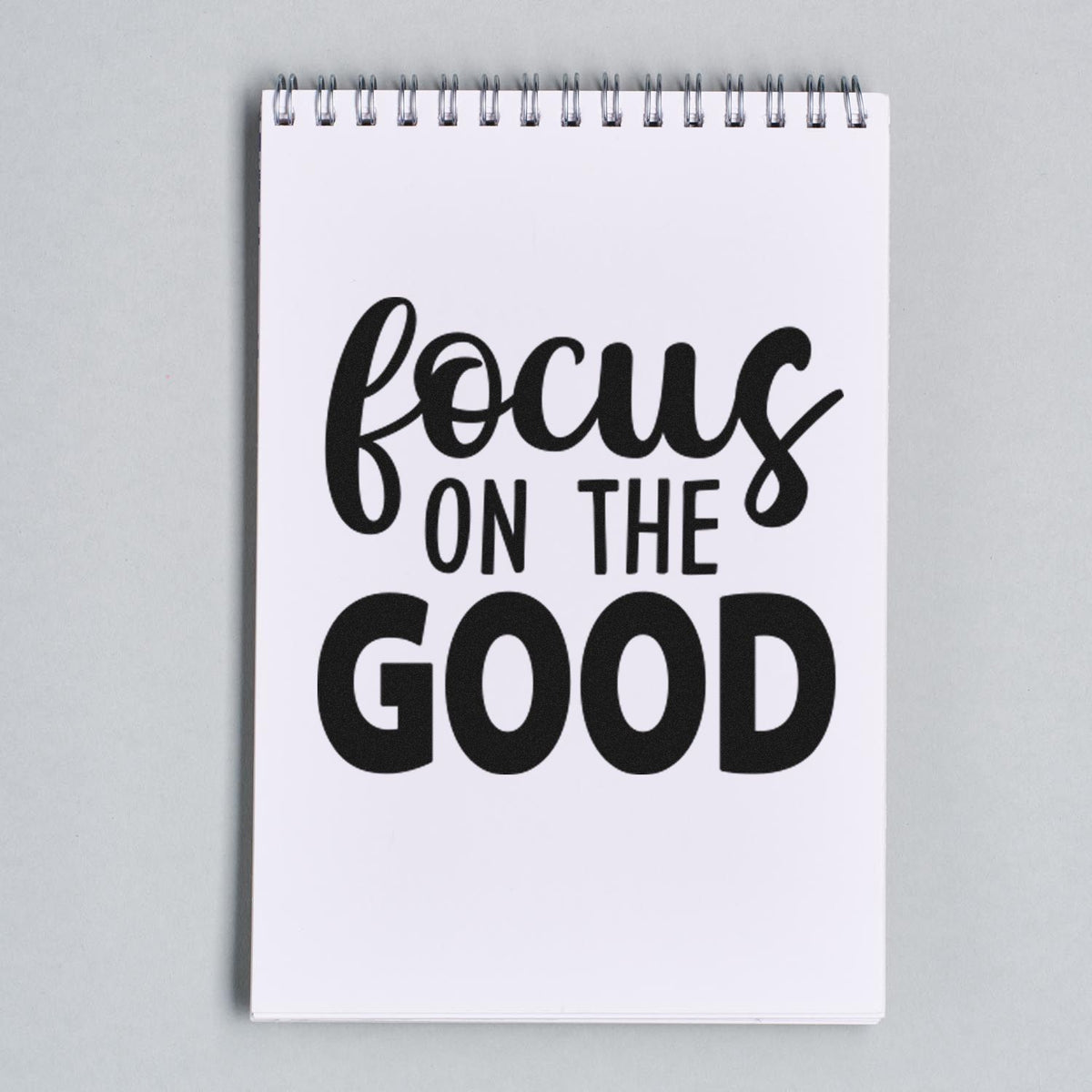Rubber stamp design with focus on the good in bold lettering on a spiral notebook page.