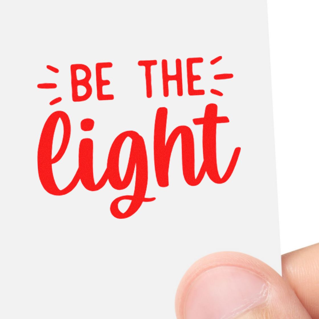 Red Be the Light rubber stamp impression in bold red on white paper, held in hand.