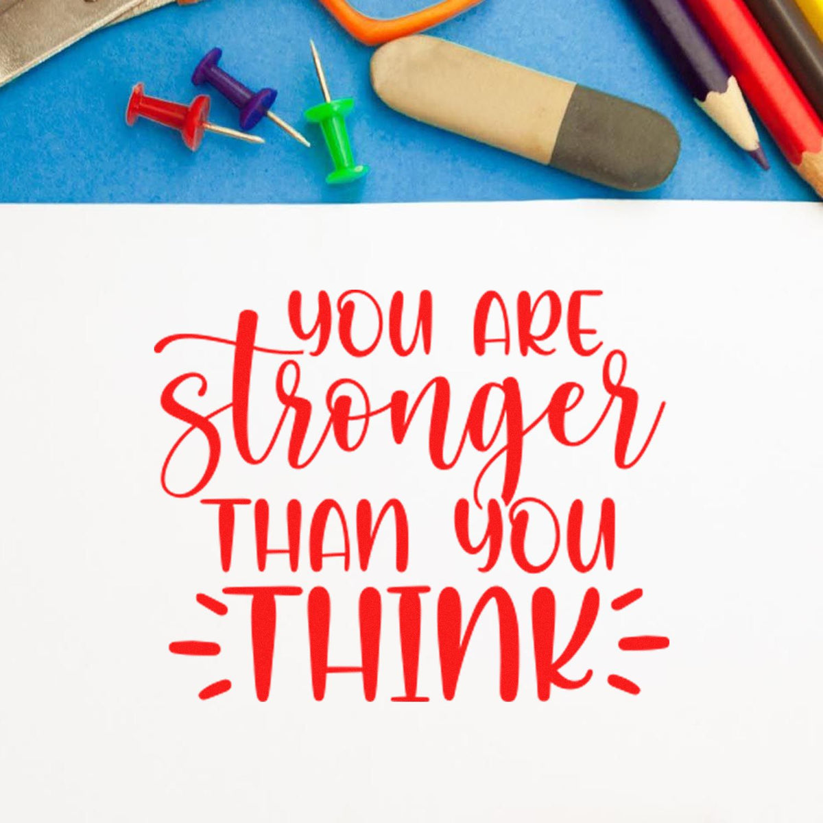 Inspirational rubber stamp quote reading You are stronger than you think in red on white paper.