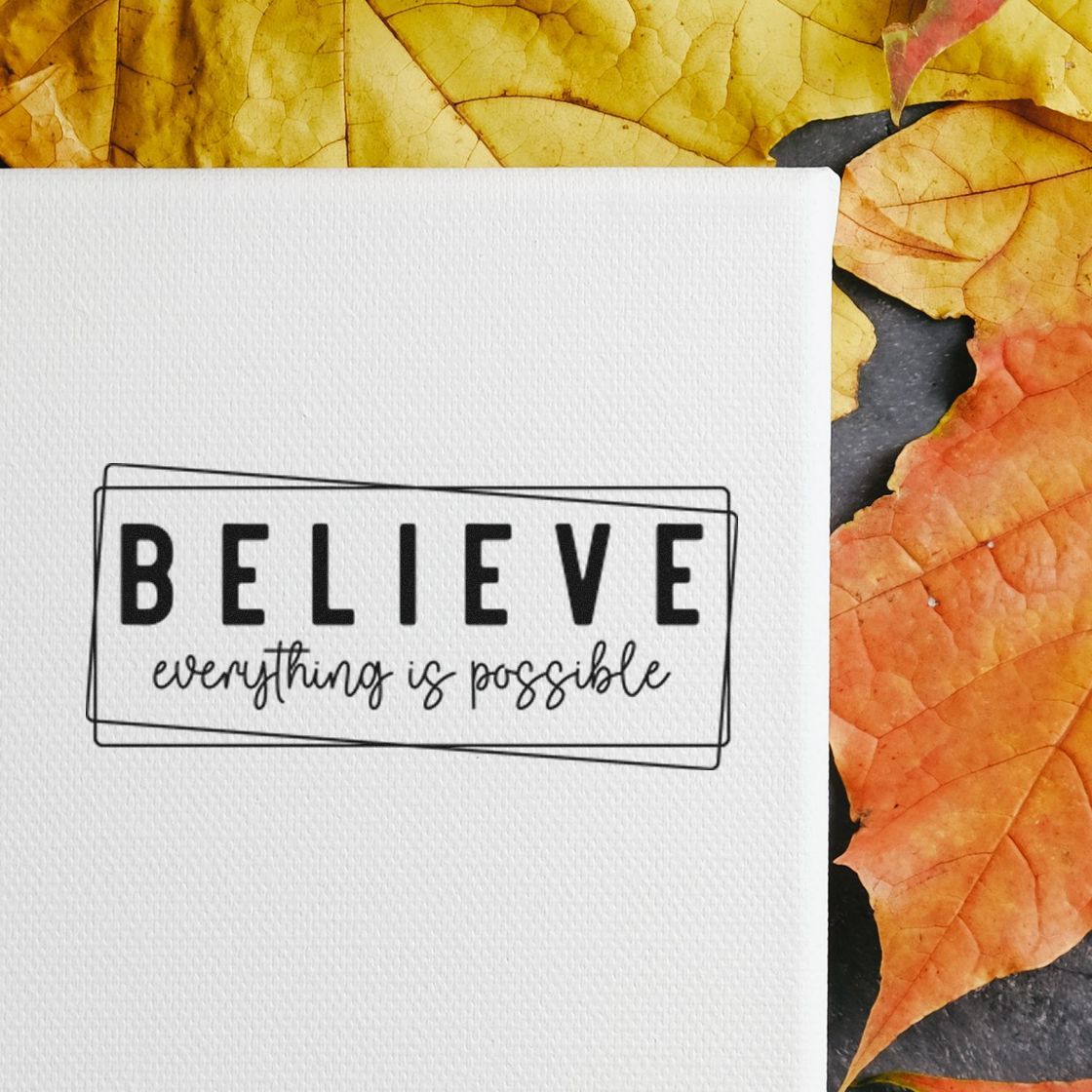 Inspirational rubber stamp design reading Believe everything is possible on white paper with autumn leaves.
