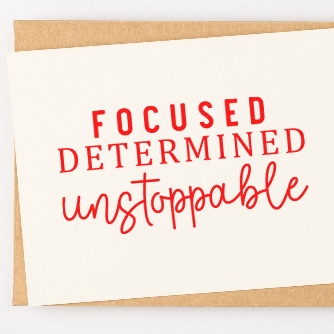 Red motivational rubber stamp reading Focused, Determined, Unstoppable on a card.
