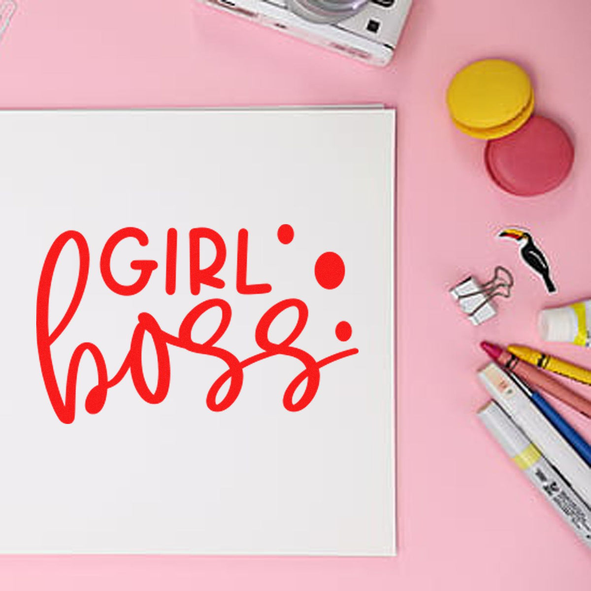 Girl Boss red rubber stamp design on white paper, surrounded by pink craft supplies for custom motivational rubber stamps