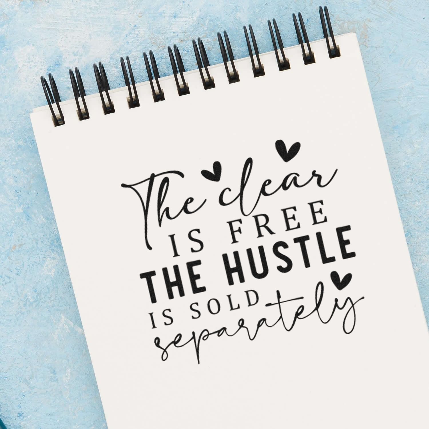 Inspirational rubber stamp quote design on a spiral notebook, with bold hand-lettered typography and heart accents.