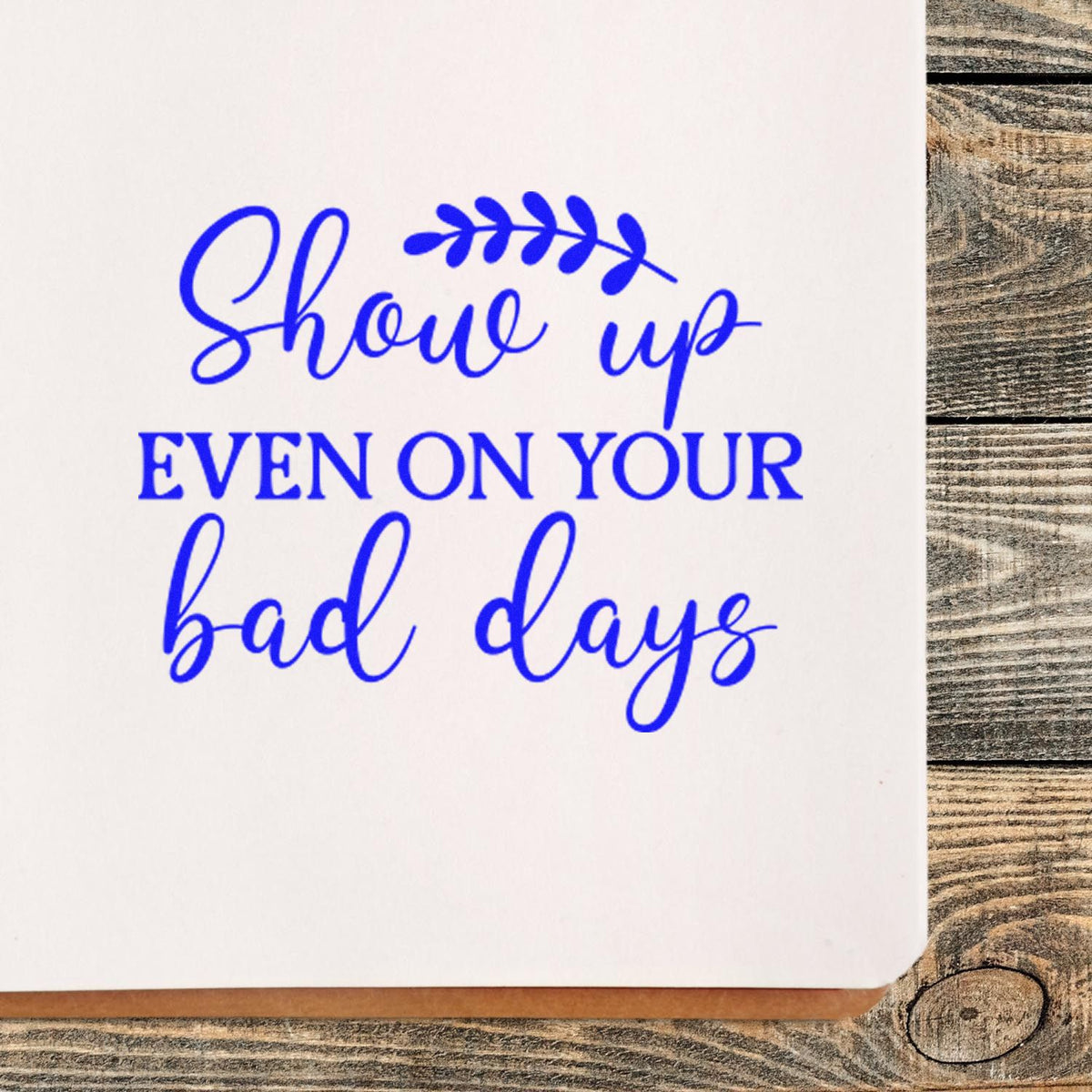 Motivational rubber stamp impression reading Show up even on your bad days in blue ink on white paper.