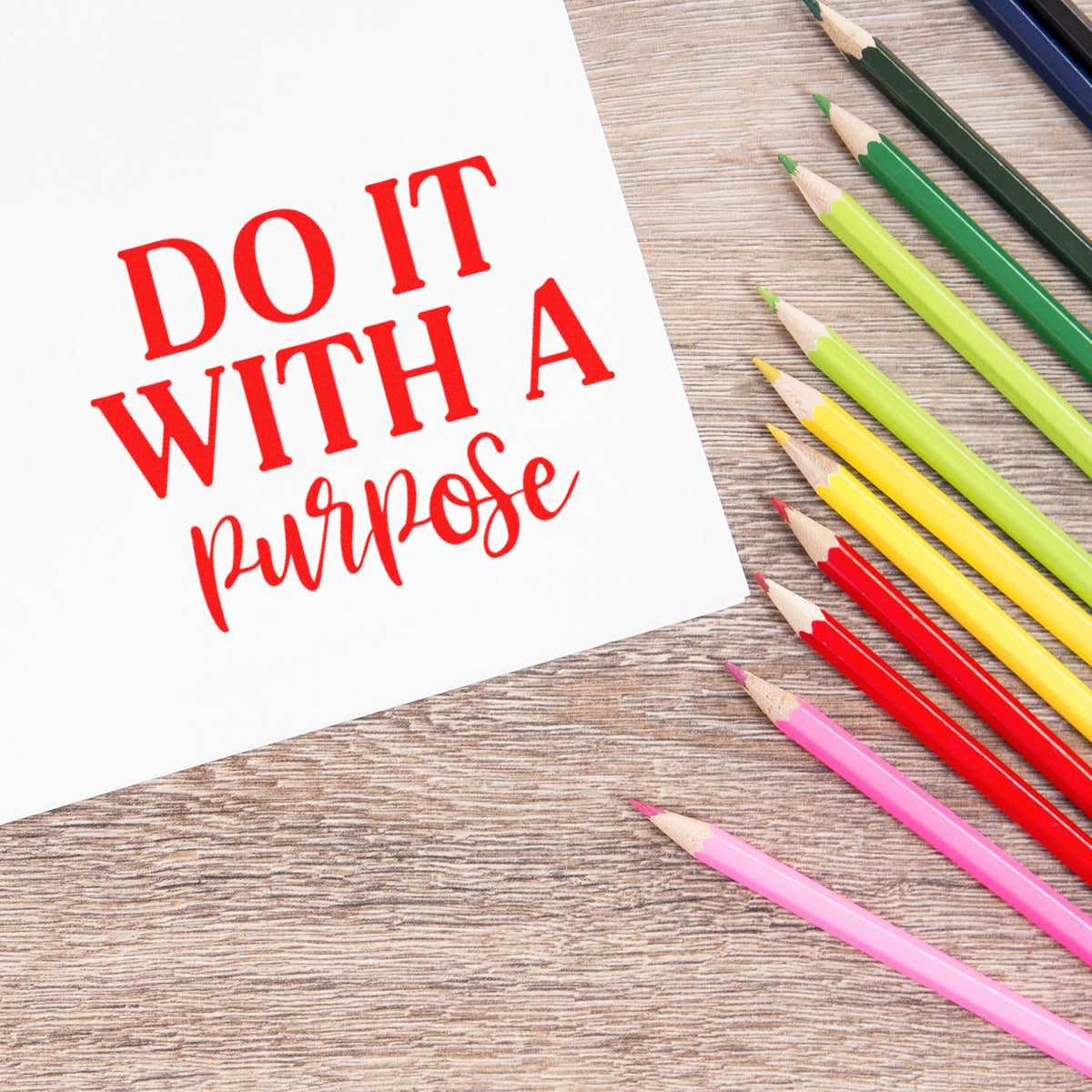 Motivational rubber stamp design reading Do It With a Purpose with colorful pencils on a wood background.