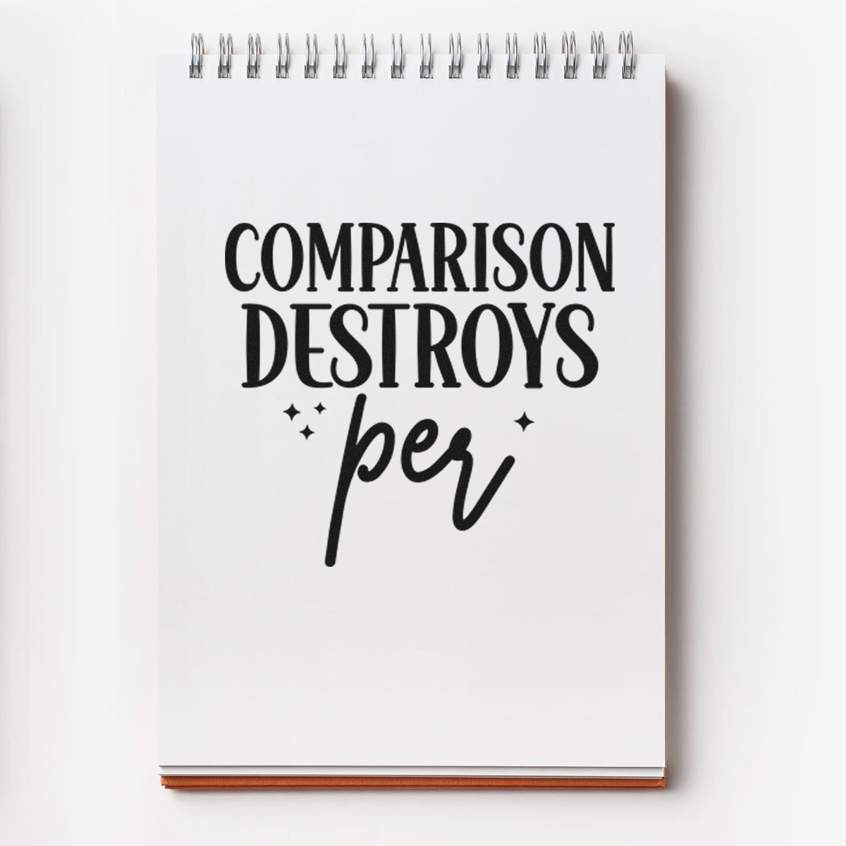 Rubber stamp design on notebook page with bold quote, Comparison Destroys Per, in black lettering.