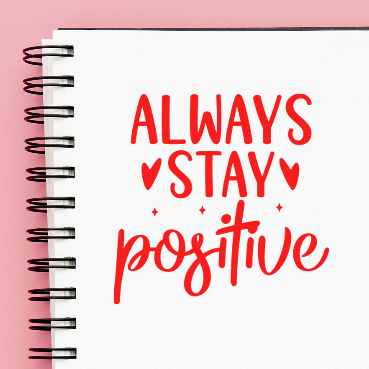 Motivational rubber stamp design with red Always Stay Positive text on a spiral notebook page.