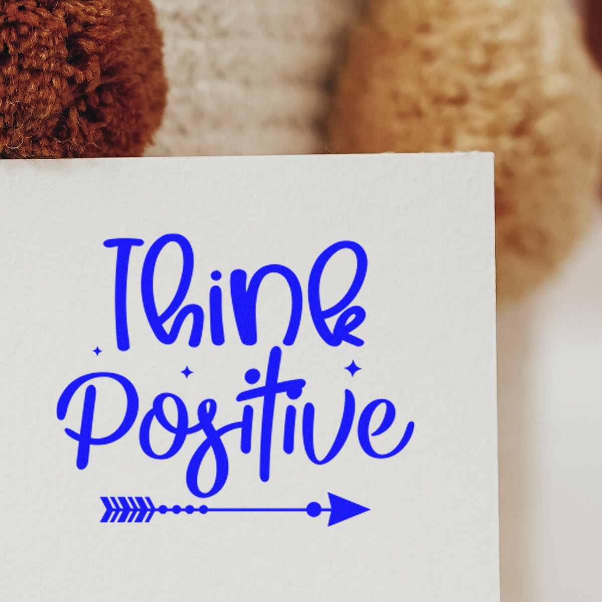 Blue Think Positive custom rubber stamp impression on paper with arrow accent for motivational crafts and stationery.
