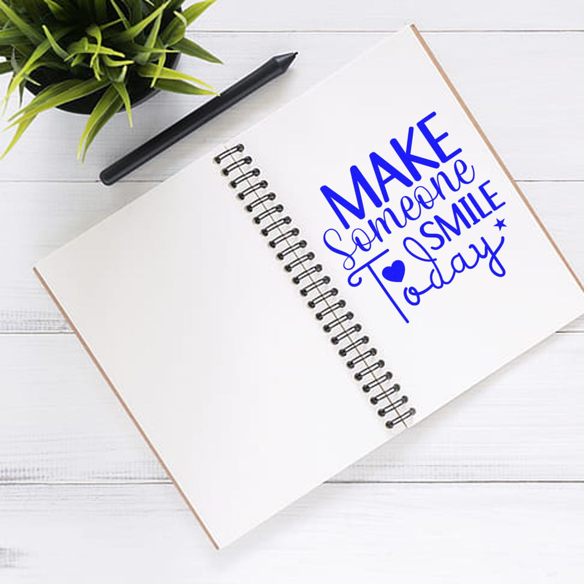 Custom rubber stamp design reading Make Someone Smile Today on a spiral notebook for inspirational stationery.