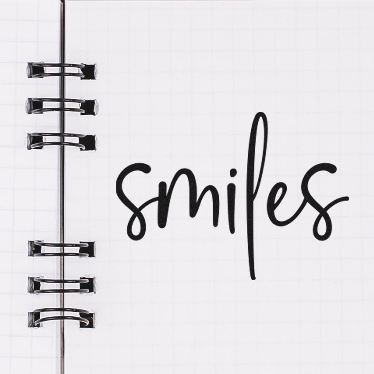 Smiles Simple Brush Script Lettering Slim Pre-Inked Stamp imprint stamped in black ink. The word "smiles" appears alone in casual brush script.