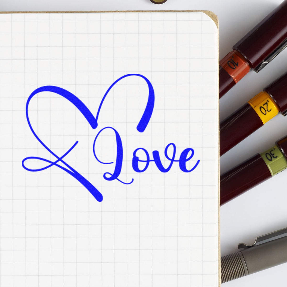 Blue heart Love rubber stamp impression on notebook page, with assorted date stamps for custom craft projects.