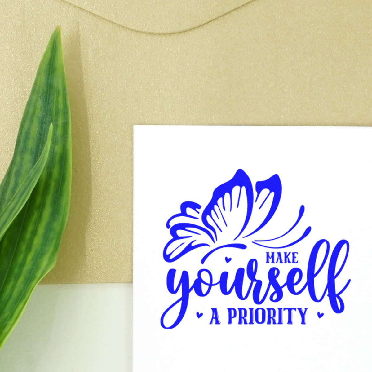 Blue butterfly rubber stamp impression with Make yourself a priority inspirational quote on white paper.