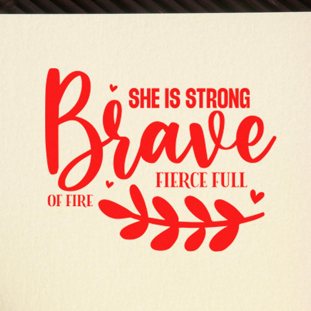 Motivational rubber stamp design with red text She is strong, brave, fierce, full of fire and heart accents.