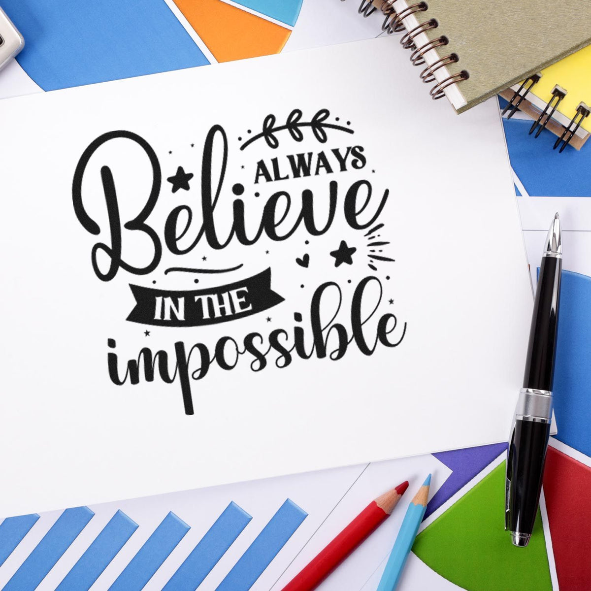 Inspirational rubber stamp design reading Always Believe in the Impossible on stationery with pens and color swatches.
