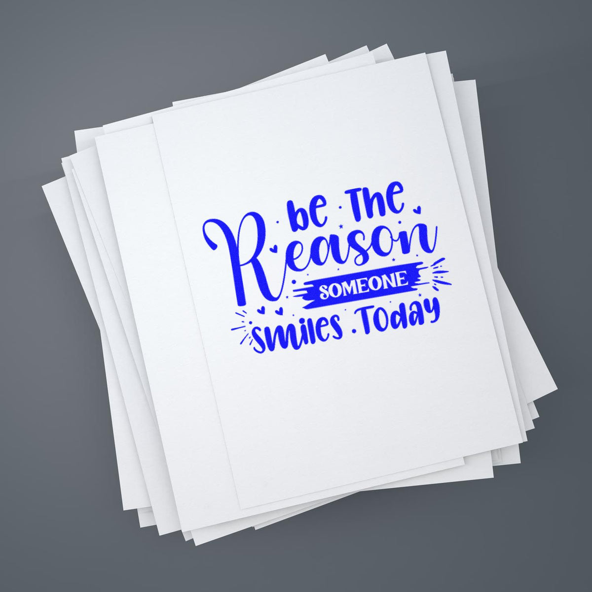 Custom blue rubber stamp design on stacked paper reading Be the Reason Someone Smiles Today.
