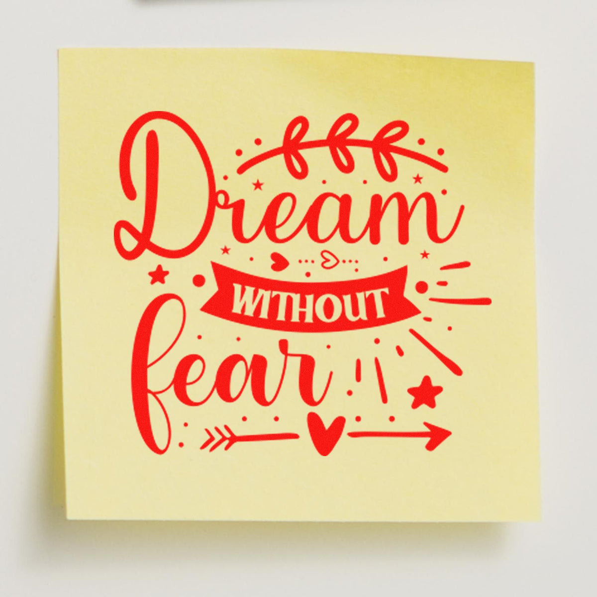 Dream Without Fear decorative rubber stamp design with red script, hearts and arrows on yellow sticky note.