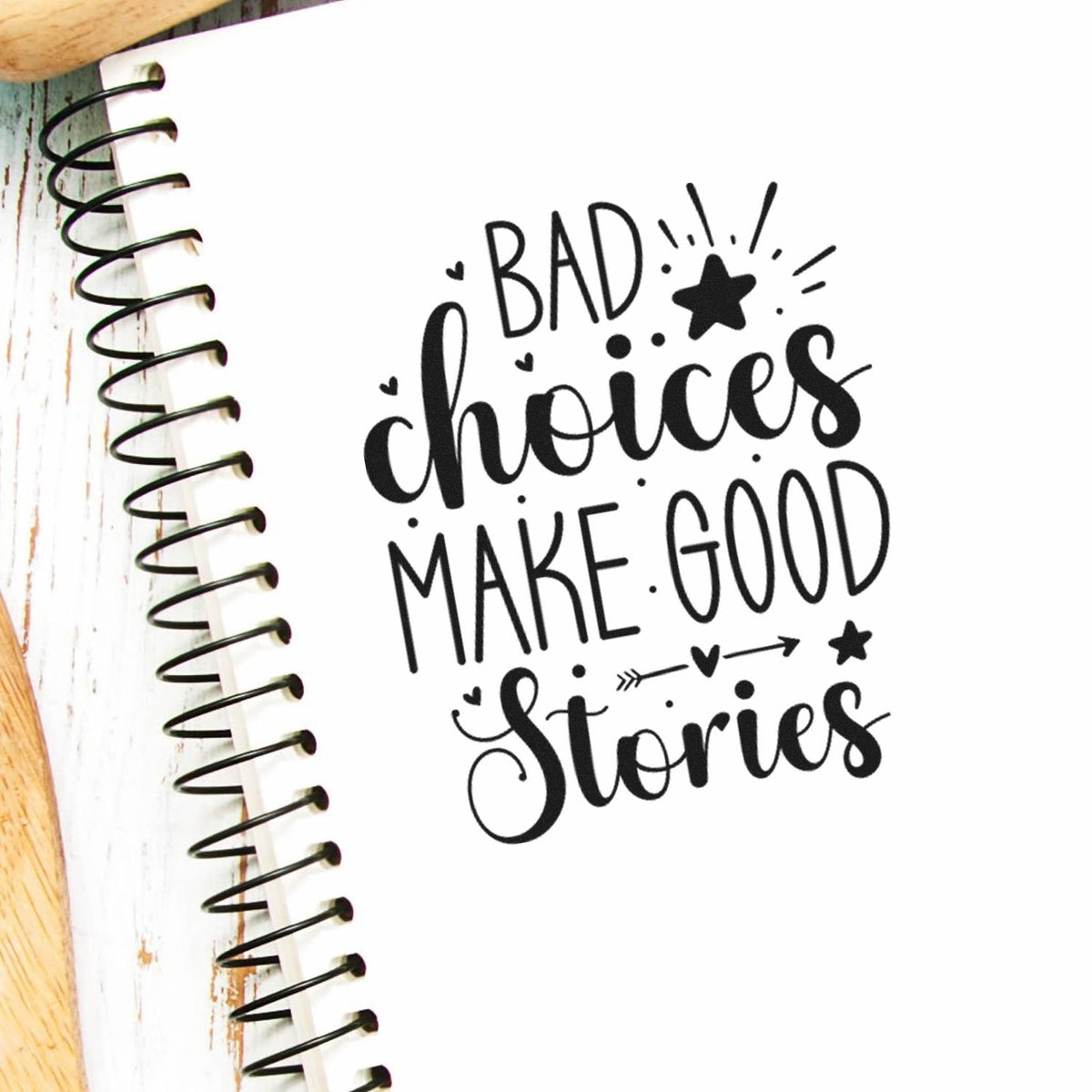 Bad Choices Make Good Stories With Stars PSI Pre-Inked Stamp imprint stamped in black ink. The phrase "Bad choices make good stories" includes stars, a heart-detailed arrow, dots, and rays.