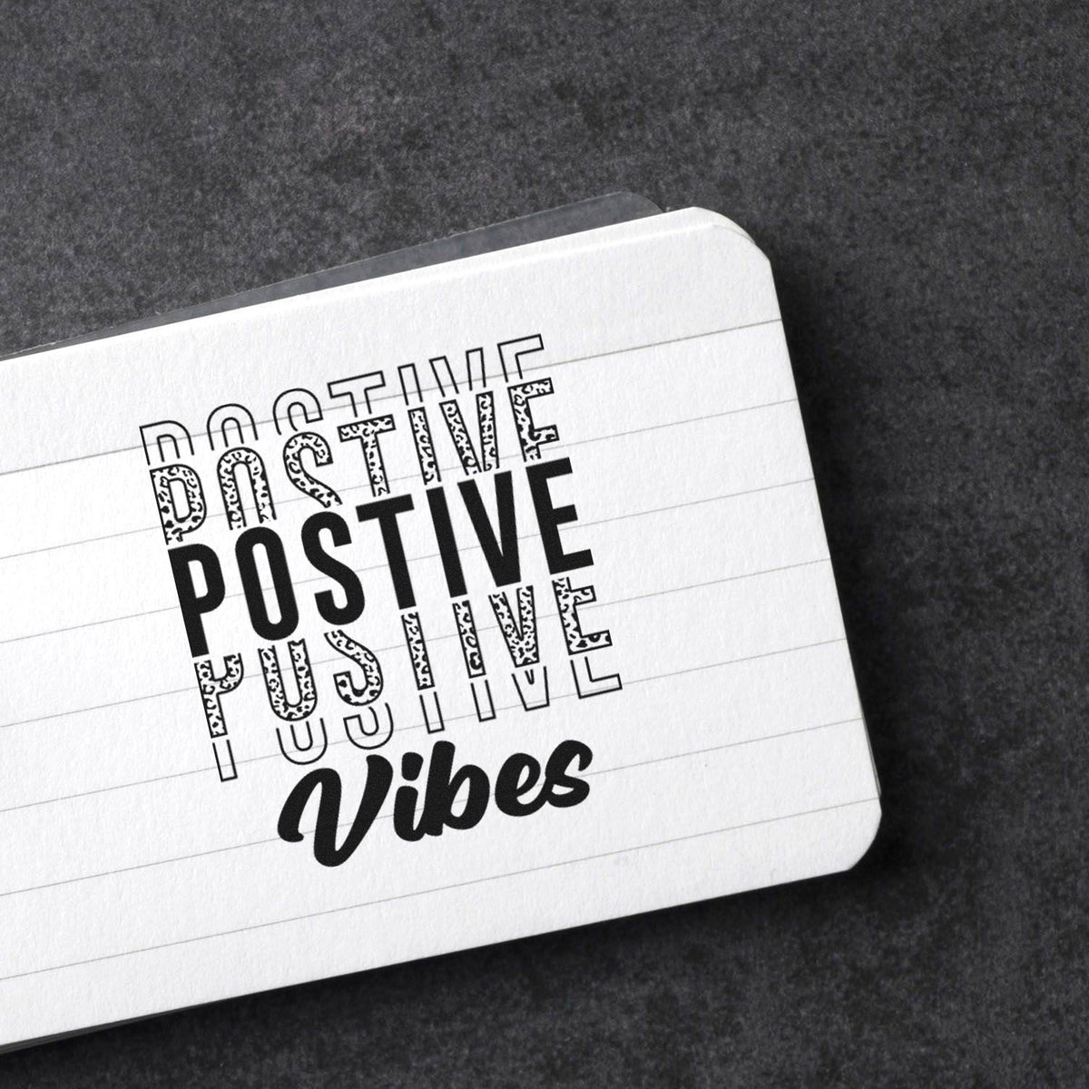 Positive Vibes rubber stamp impression on lined paper, showcasing a bold motivational stamp design for stationery and crafts