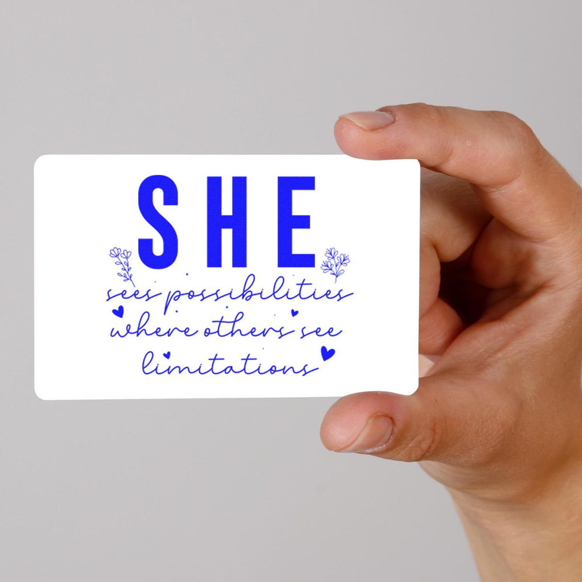 Custom rubber stamp design reading SHE sees possibilities where others see limitations in blue, held by hand.