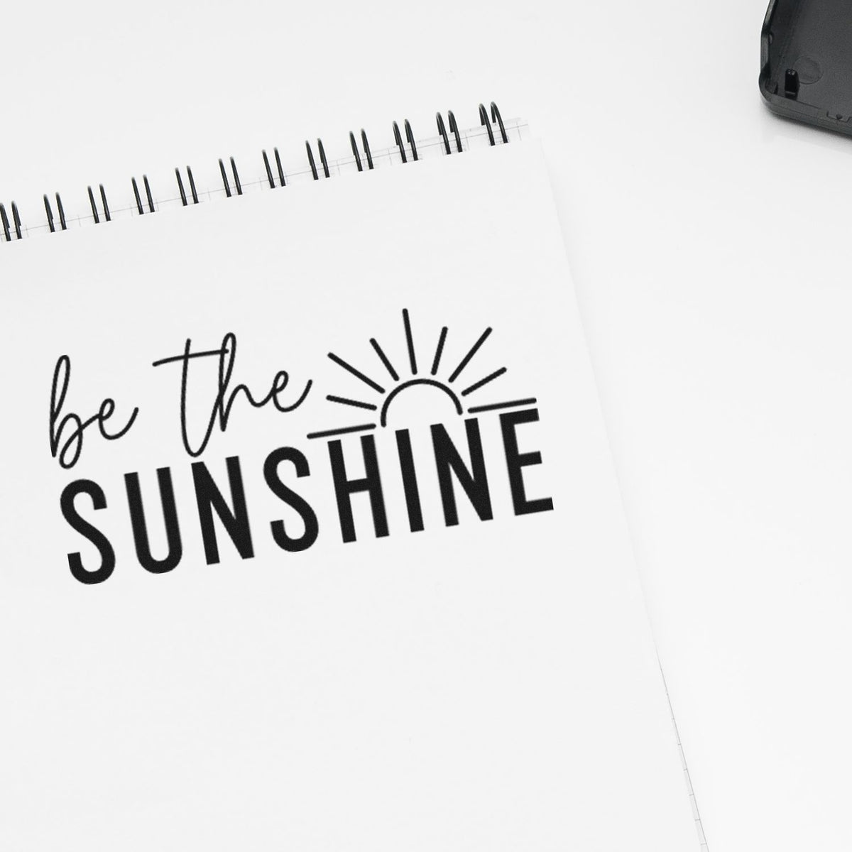 Be the Sunshine rubber stamp design on a spiral notebook with sun graphic, ideal for motivational custom stamps.