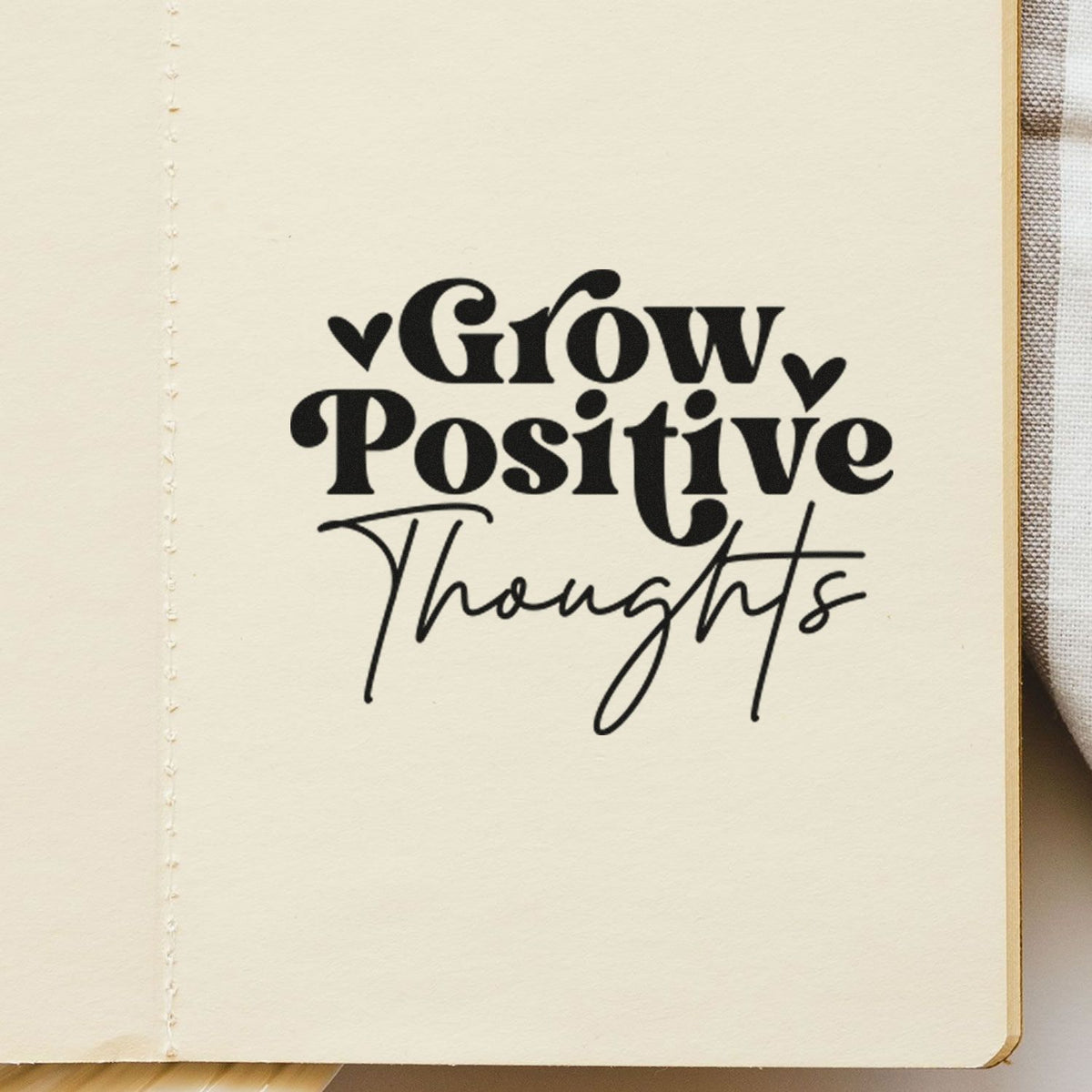 Inspirational rubber stamp reading Grow Positive Thoughts with hearts on notebook page for journaling.