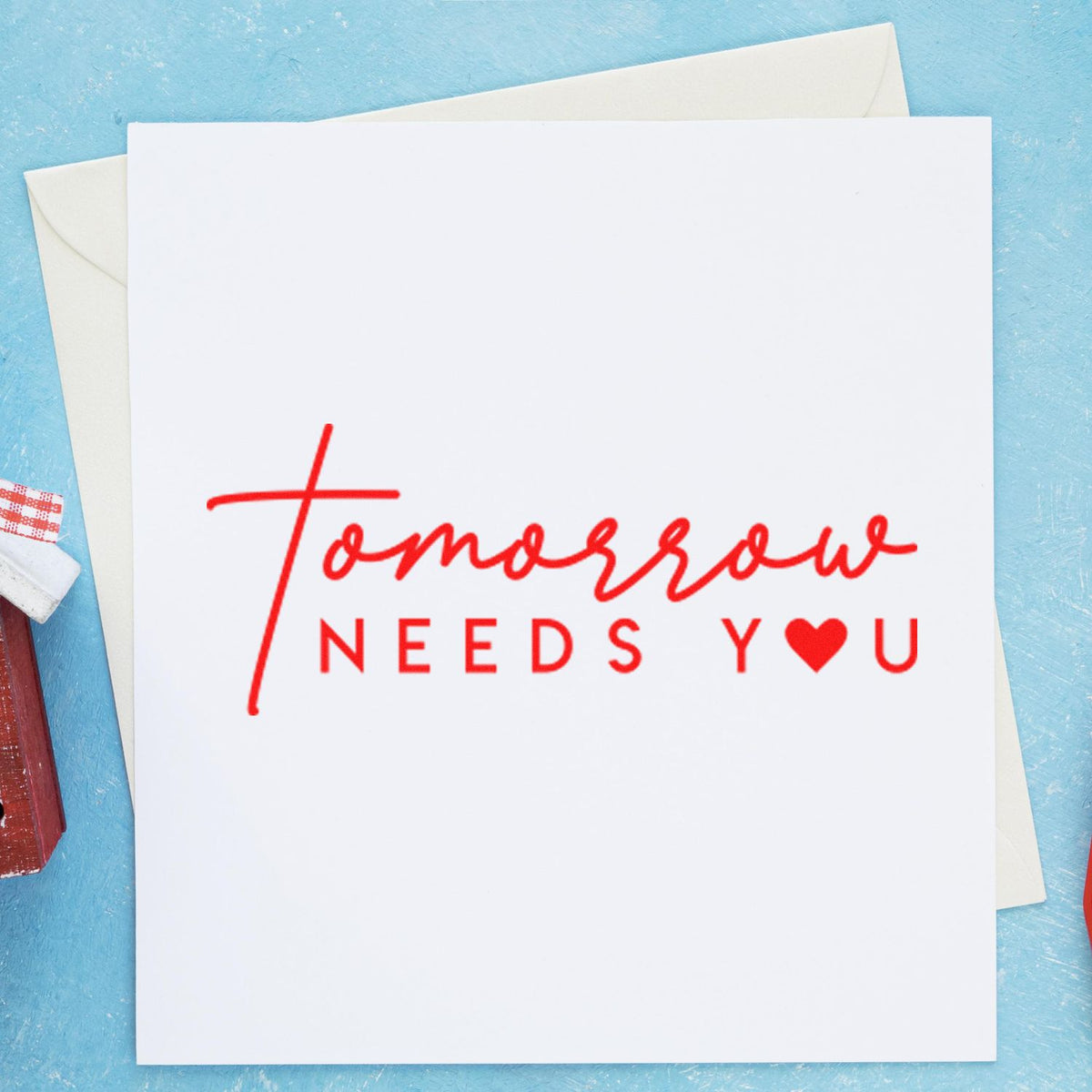 Red rubber stamp-style sentiment on card reading Tomorrow Needs You with a heart, perfect for handmade encouragement cards.