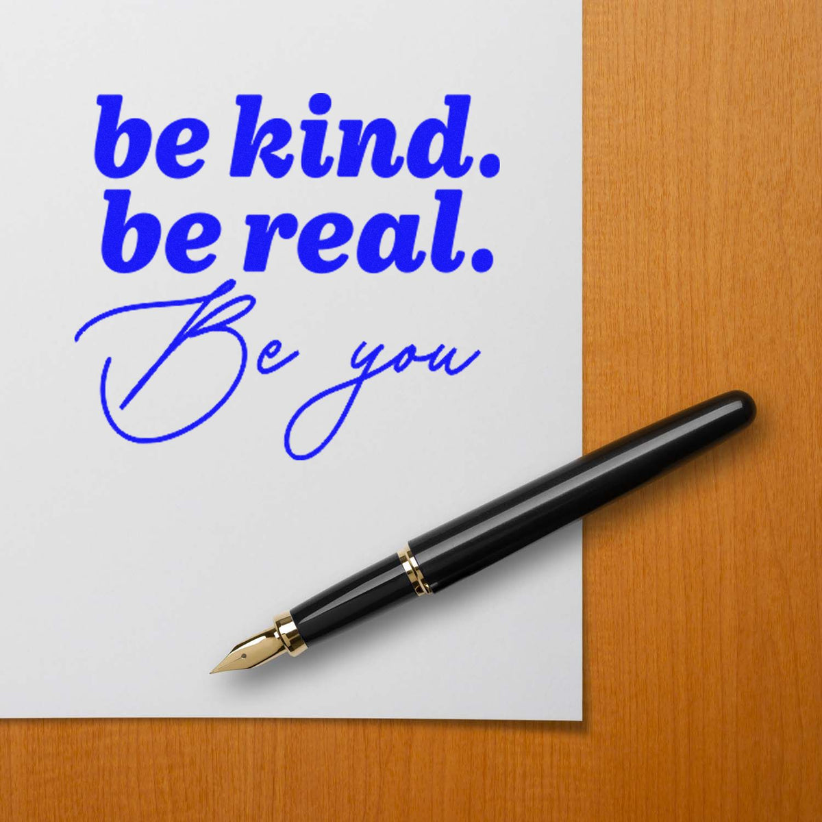 Custom rubber stamp impression reading be kind. be real. Be you on paper beside a fountain pen.
