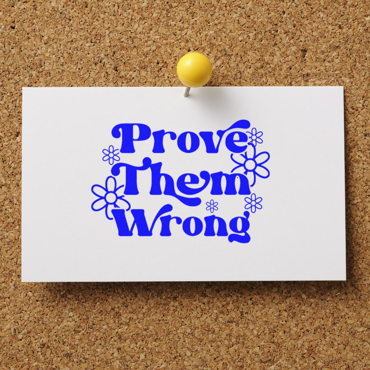 Blue Prove Them Wrong rubber stamp design with floral accents pinned to corkboard for motivational crafting.