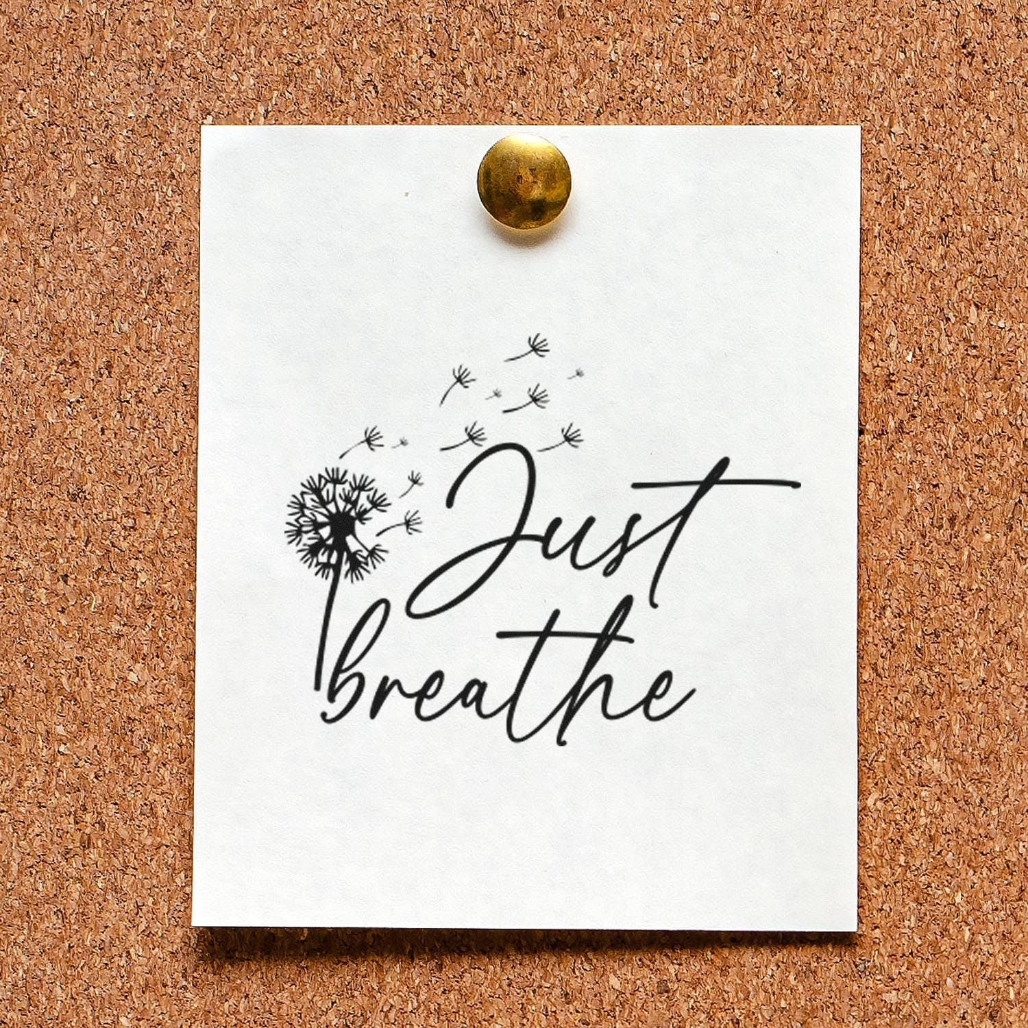 Just Breathe rubber stamp with dandelion design, stamped on white paper pinned to a cork board.