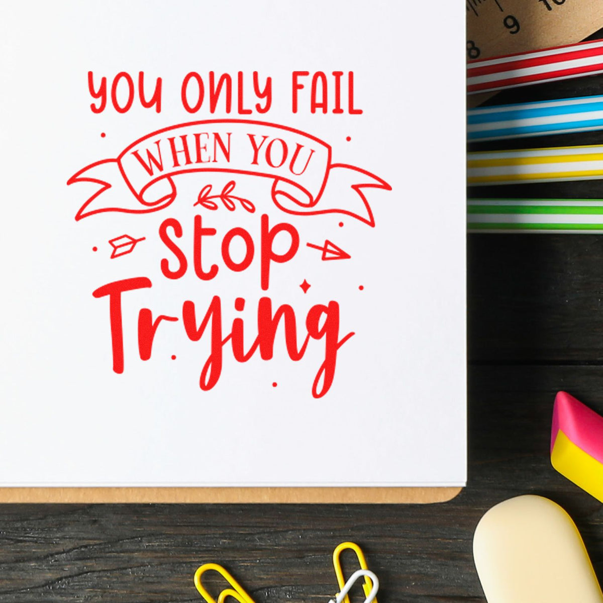Motivational rubber stamp impression reading You only fail when you stop trying in red on a notebook.