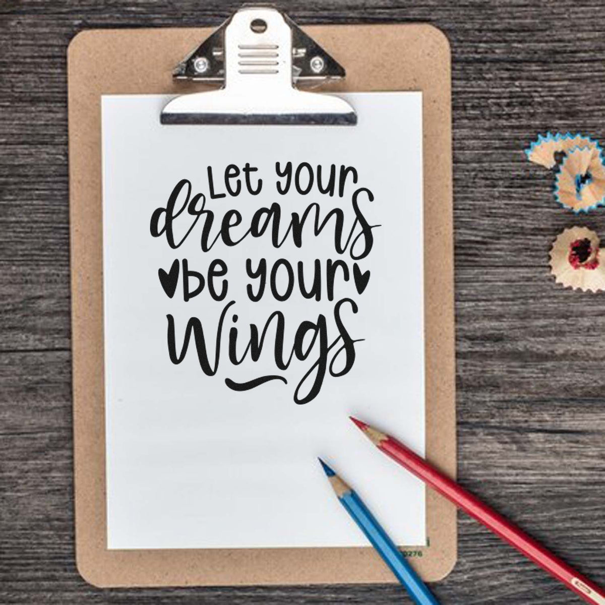 Inspirational rubber stamp quote reading "Let your dreams be your wings" on clipboard for journaling and craft projects.