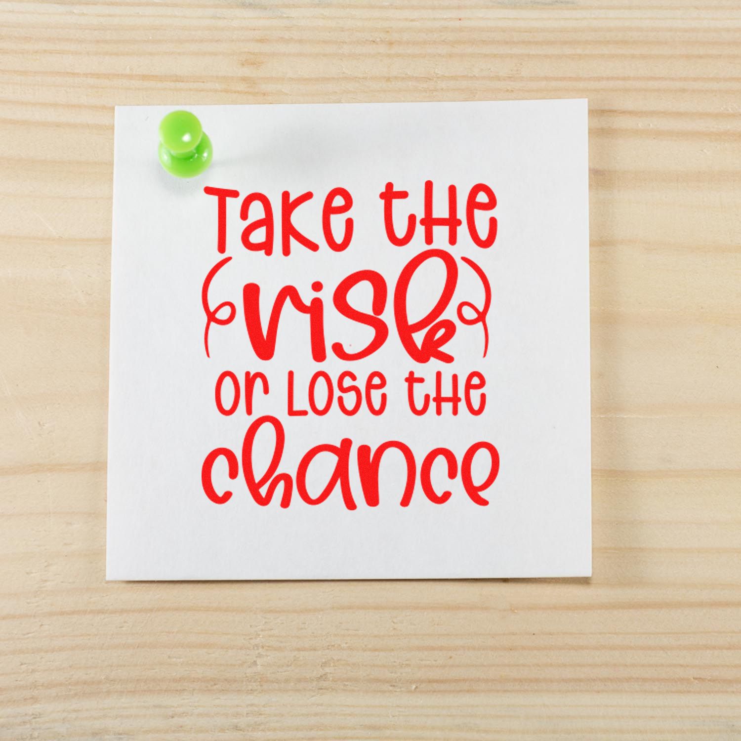 Motivational rubber stamp design with red quote, Take the risk or lose the chance, on a pinned white note.