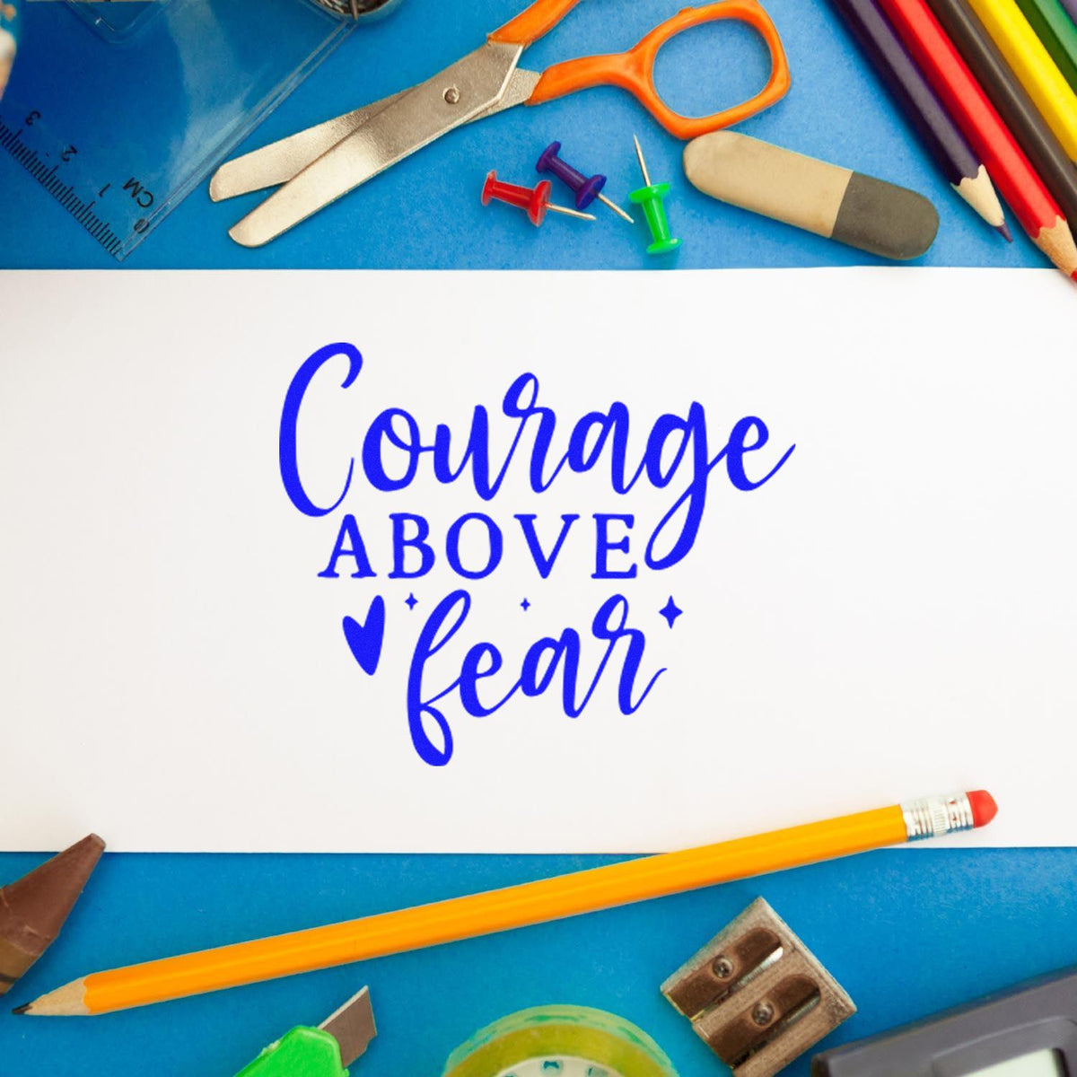 Inspirational rubber stamp design reading Courage Above Fear surrounded by craft supplies and school tools.