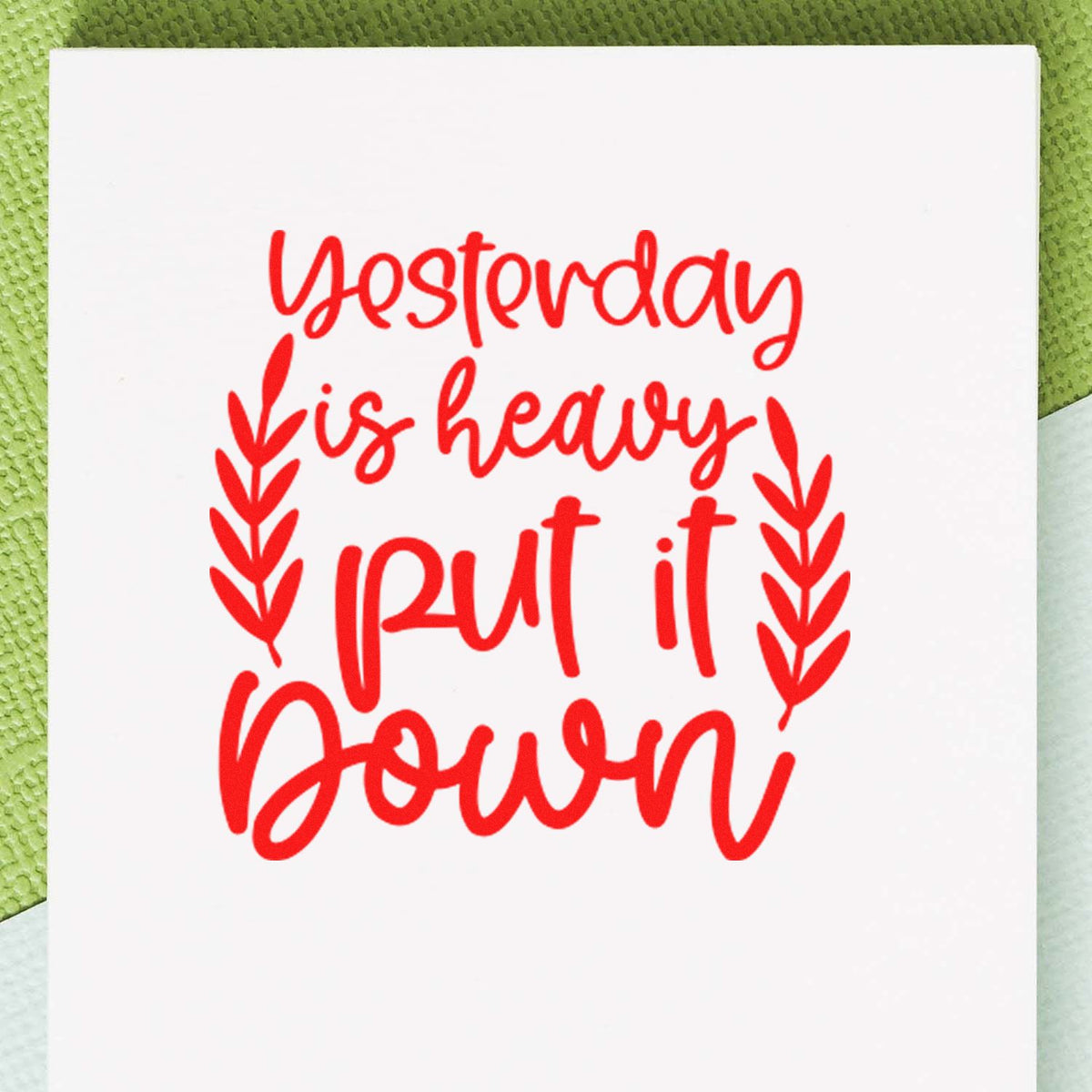 Red motivational rubber stamp reading Yesterday is heavy, put it down with leaf accents on white card.
