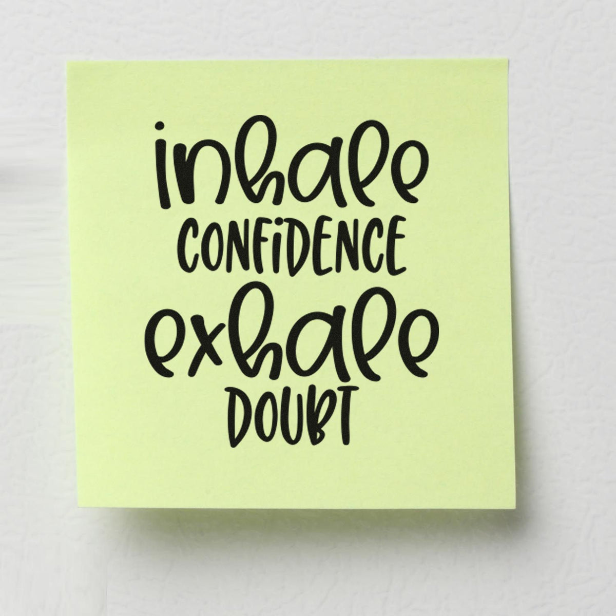 Inspirational rubber stamp with quote Inhale Confidence, Exhale Doubt on a light green sticky note.