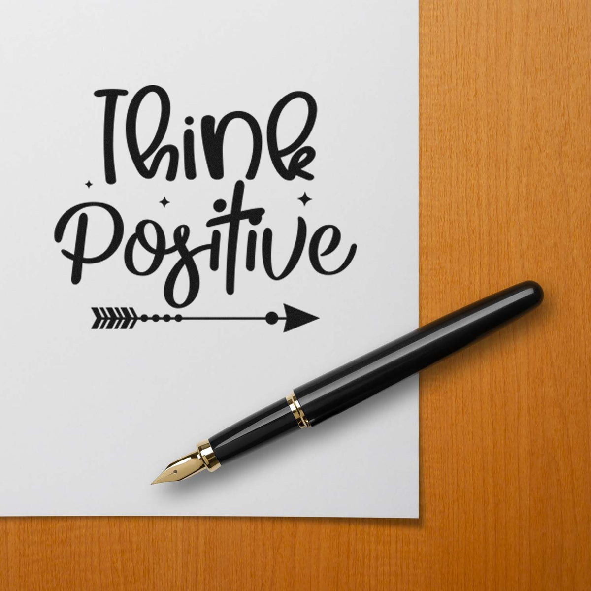 Think Positive rubber stamp design mockup with handwritten quote, arrow accent, and fountain pen on paper.