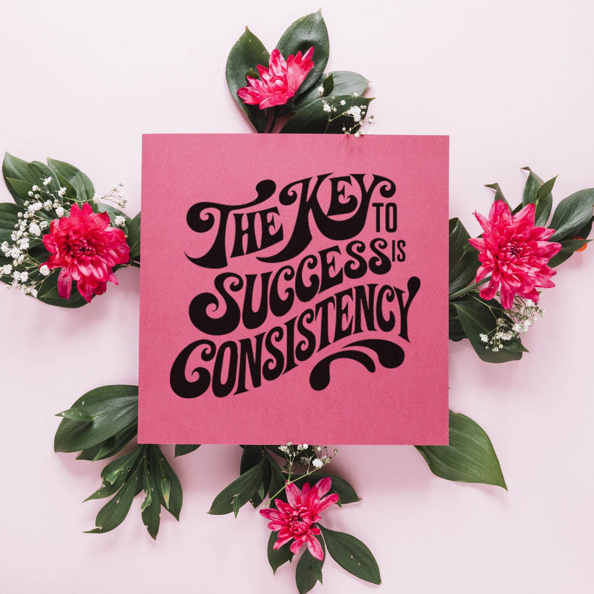 Motivational rubber stamp design reading The Key to Success is Consistency in bold black lettering on a pink floral background.