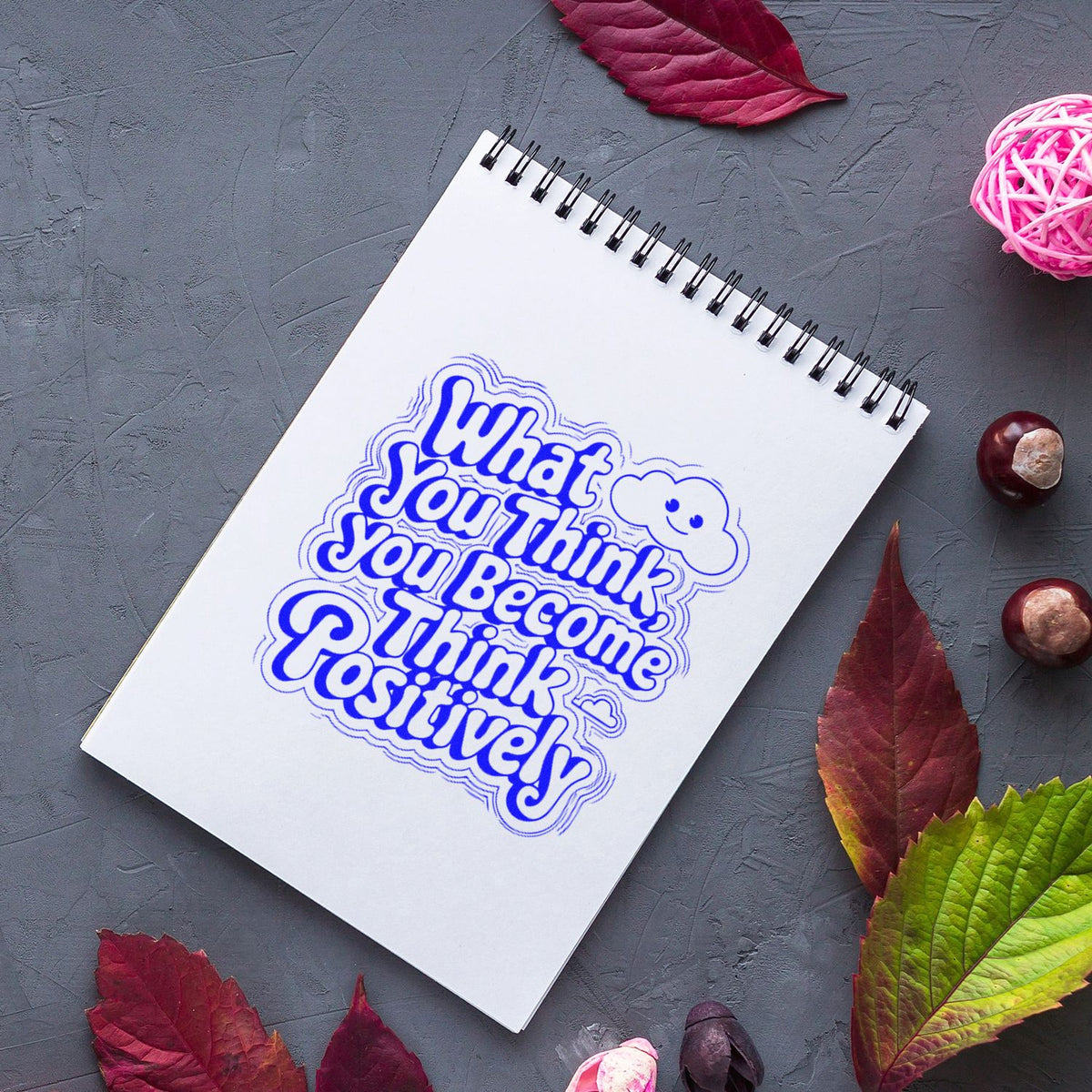 Motivational rubber stamp imprint reading What You Think You Become Think Positively on a spiral notebook.